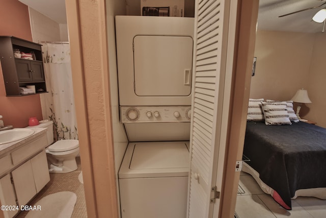 laundry room with light tile patterned floors, stacked washer and dryer, ceiling fan, and sink