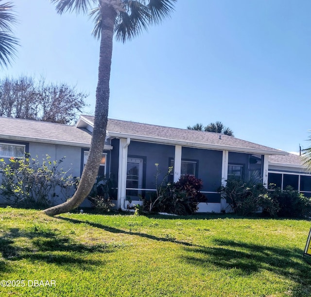 back of property with a sunroom, a lawn, and stucco siding