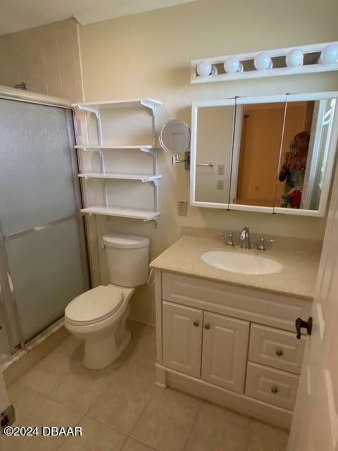 bathroom featuring tile patterned flooring, vanity, an enclosed shower, and toilet