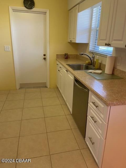 kitchen with white cabinetry, sink, stainless steel dishwasher, backsplash, and light tile patterned floors