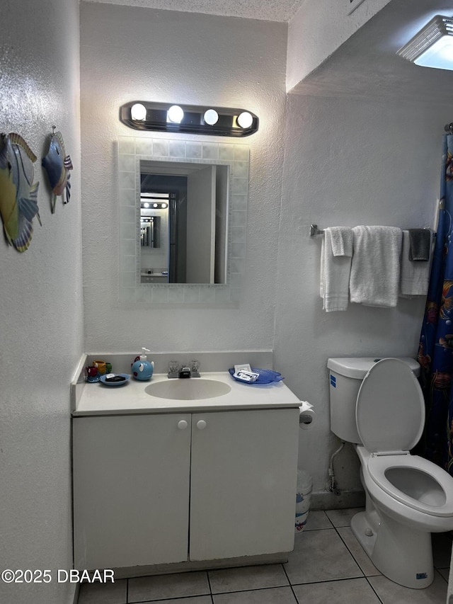 bathroom with toilet, tile patterned flooring, and vanity