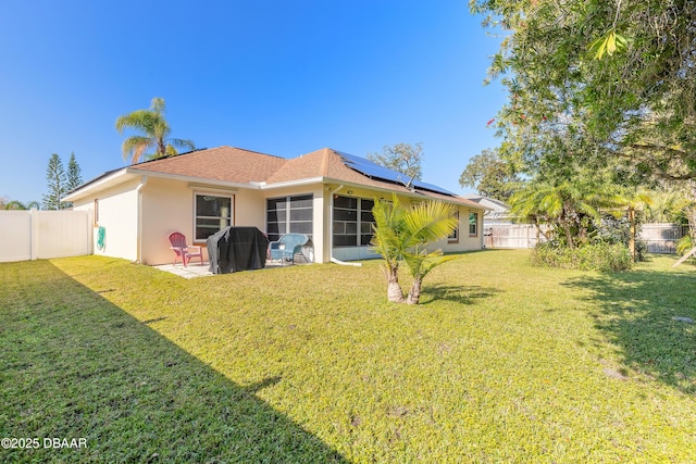 rear view of property with solar panels, a patio area, and a yard