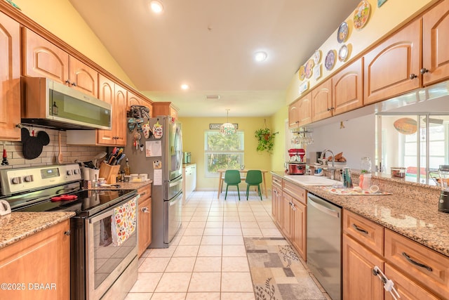 kitchen featuring appliances with stainless steel finishes, hanging light fixtures, lofted ceiling, sink, and light tile patterned flooring