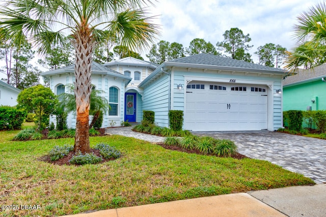 view of front facade featuring an attached garage, a front lawn, and decorative driveway