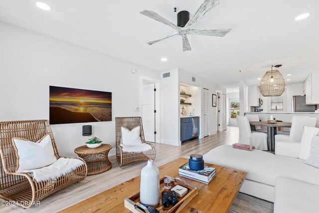 living room with ceiling fan, wine cooler, and light hardwood / wood-style flooring