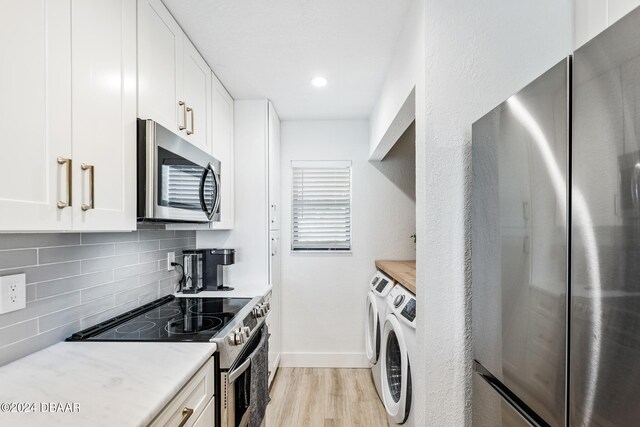 kitchen featuring light hardwood / wood-style floors, backsplash, white cabinetry, appliances with stainless steel finishes, and washer and dryer