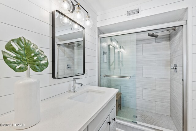 bathroom with vanity, wooden walls, and an enclosed shower