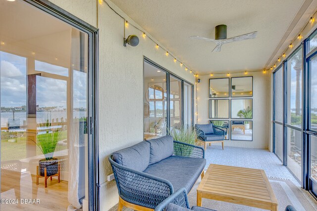 sunroom / solarium featuring a water view and ceiling fan