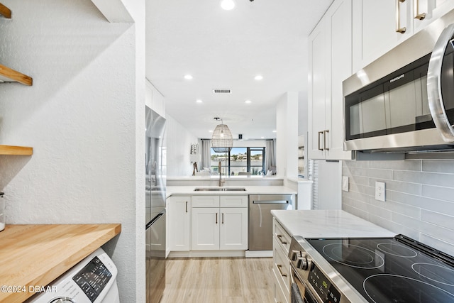 kitchen with light hardwood / wood-style floors, sink, appliances with stainless steel finishes, light stone countertops, and white cabinets