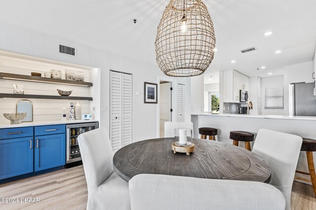 dining space featuring bar, wine cooler, and light hardwood / wood-style flooring