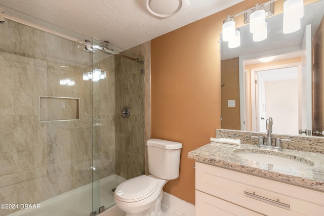 bathroom featuring vanity, a textured ceiling, toilet, and a shower with door