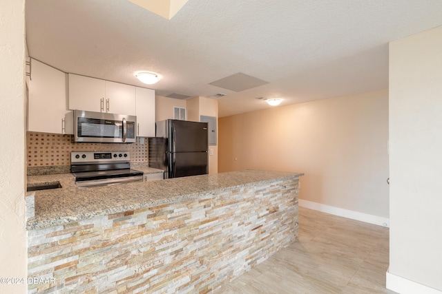 kitchen with kitchen peninsula, appliances with stainless steel finishes, white cabinetry, and light stone counters