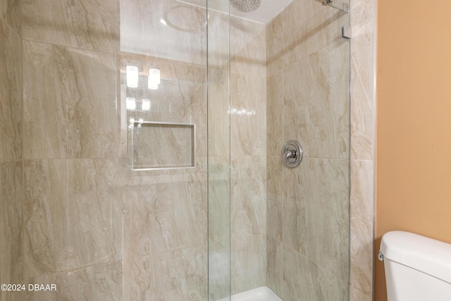 bathroom with a tile shower and toilet