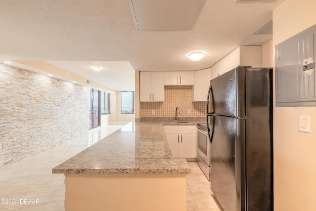 kitchen with stainless steel range with electric stovetop, black fridge, sink, tasteful backsplash, and white cabinetry