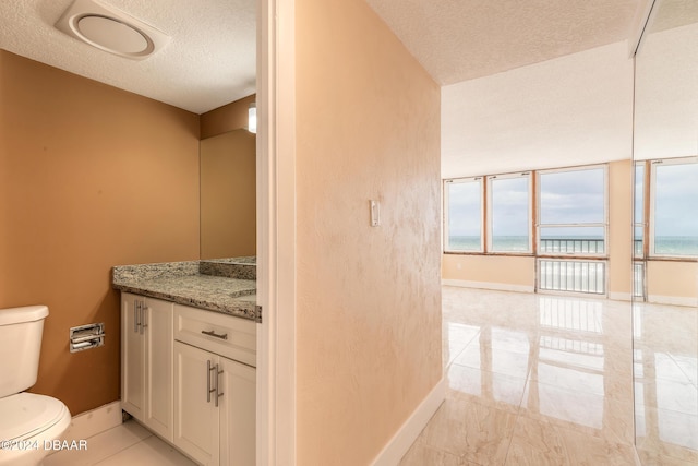 bathroom featuring a wealth of natural light, a water view, and a textured ceiling