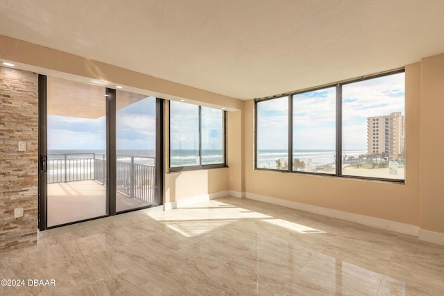 unfurnished room with a textured ceiling and a water view