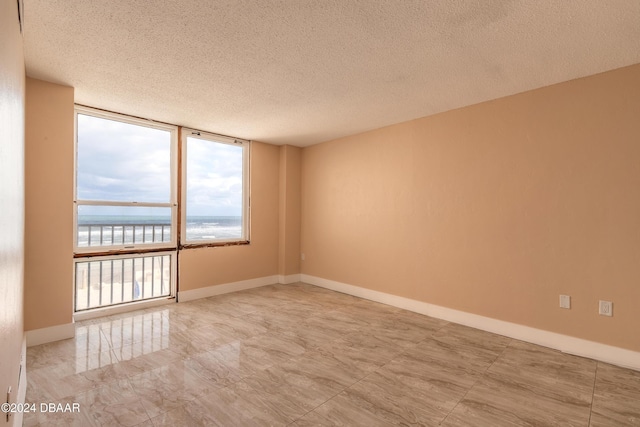 empty room featuring a textured ceiling and a water view