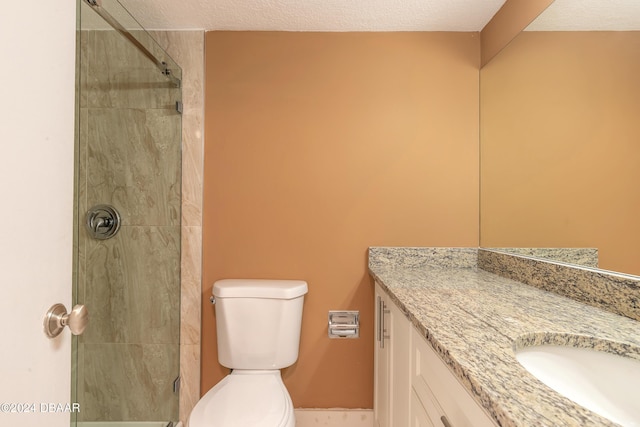 bathroom featuring vanity, toilet, a textured ceiling, and a tile shower