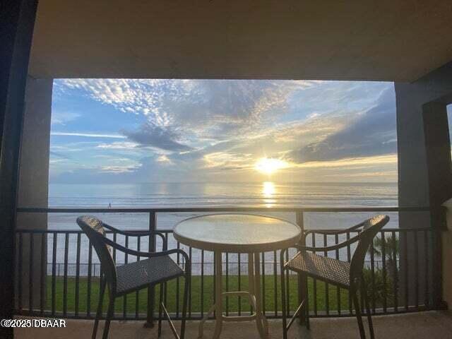 balcony at dusk featuring a water view