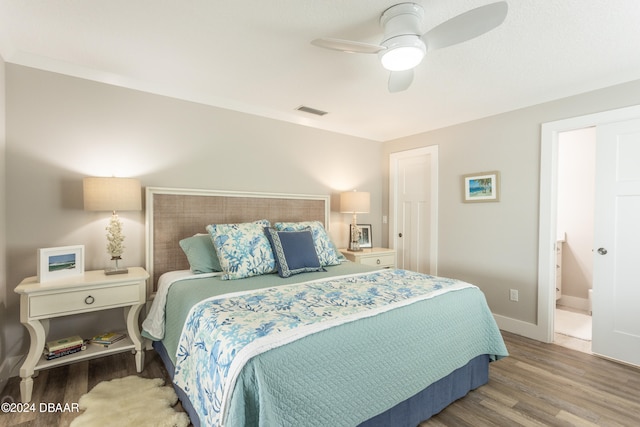 bedroom with wood-type flooring, ceiling fan, and connected bathroom