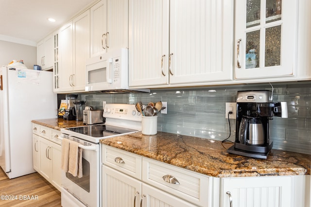 kitchen featuring dark stone countertops, backsplash, white appliances, light hardwood / wood-style flooring, and white cabinets