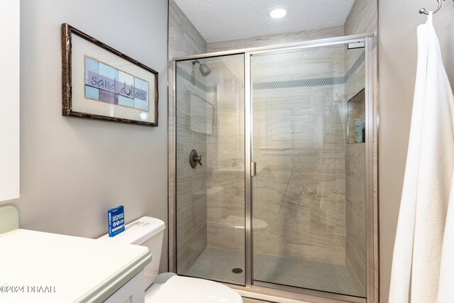 bathroom featuring walk in shower, a textured ceiling, and toilet