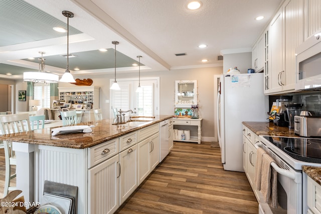 kitchen with sink, a breakfast bar area, dark hardwood / wood-style floors, dark stone countertops, and a center island