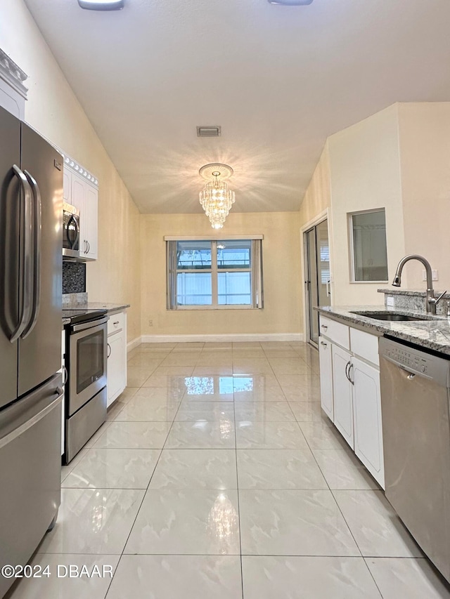 5 Wild Rose Pl, Palm Coast, FL 32164 - kitchen featuring white cabinetry, sink, appliances with stainless steel finishes, a chandelier, and vaulted ceiling