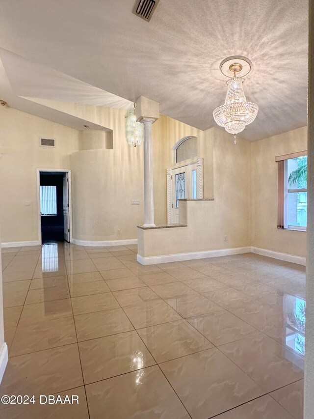 5 Wild Rose Pl, Palm Coast, FL 32164 - interior space featuring tile patterned flooring, a textured ceiling, lofted ceiling, a notable chandelier, and ornate columns
