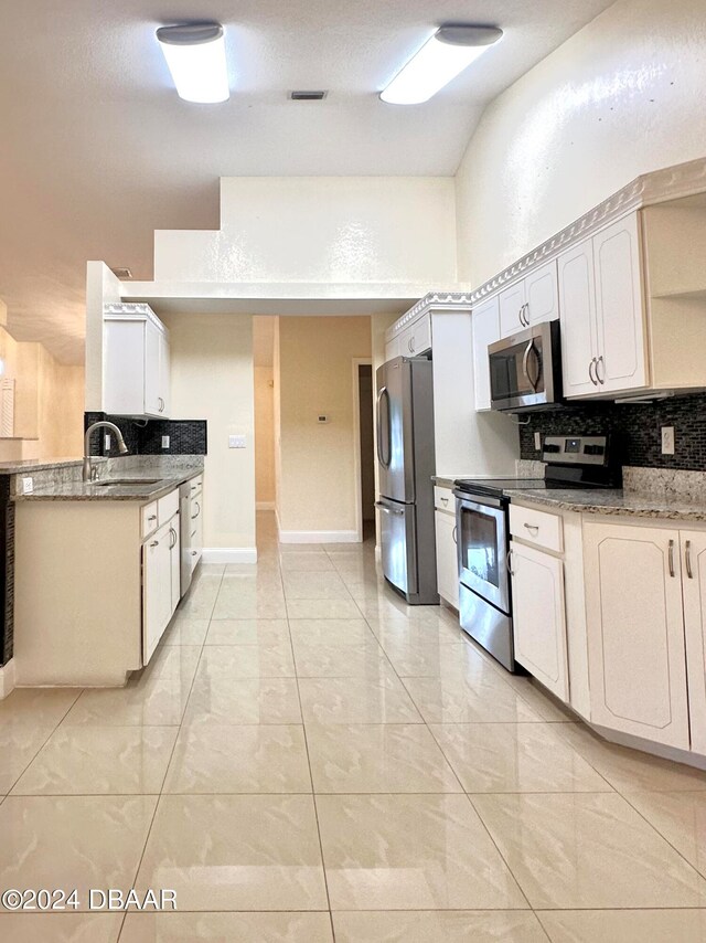 5 Wild Rose Pl, Palm Coast, FL 32164 - kitchen with stainless steel appliances, sink, dark stone countertops, white cabinets, and decorative backsplash