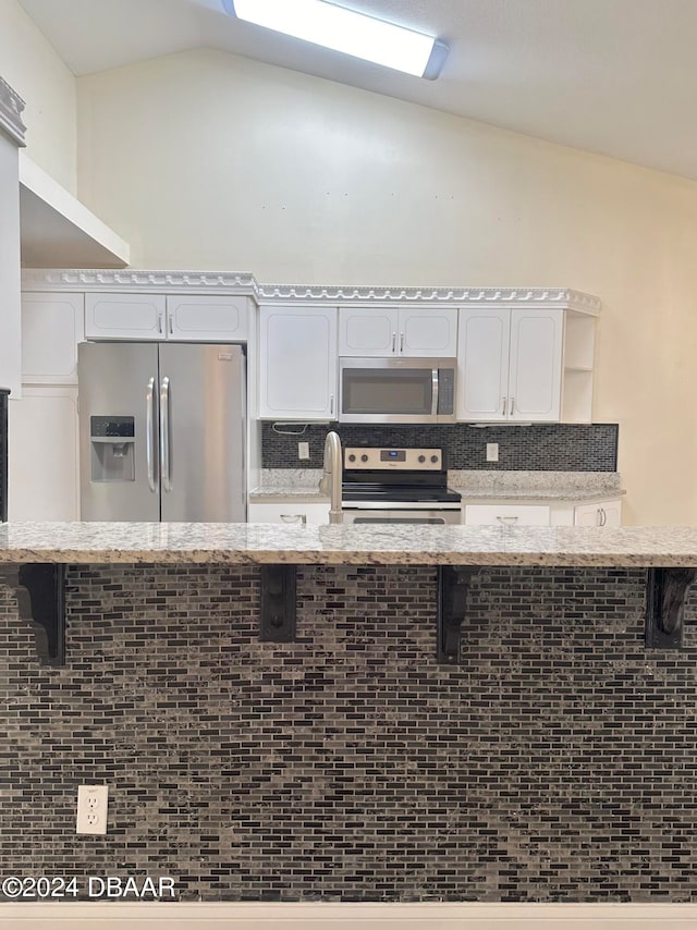 5 Wild Rose Pl, Palm Coast, FL 32164 - kitchen featuring stainless steel appliances, white cabinetry, kitchen peninsula, a kitchen bar, and lofted ceiling