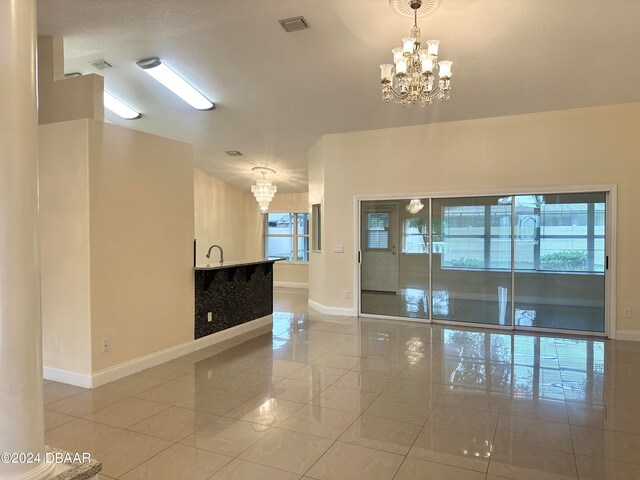 5 Wild Rose Pl, Palm Coast, FL 32164 - spare room with light tile patterned flooring, an inviting chandelier, and a healthy amount of sunlight