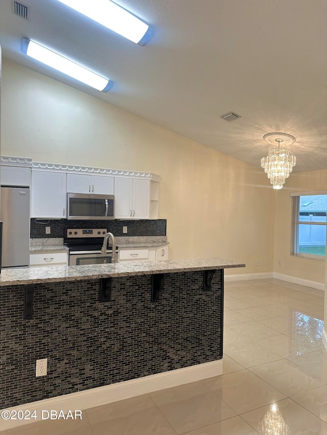 5 Wild Rose Pl, Palm Coast, FL 32164 - kitchen with white cabinetry, appliances with stainless steel finishes, a kitchen bar, and a notable chandelier
