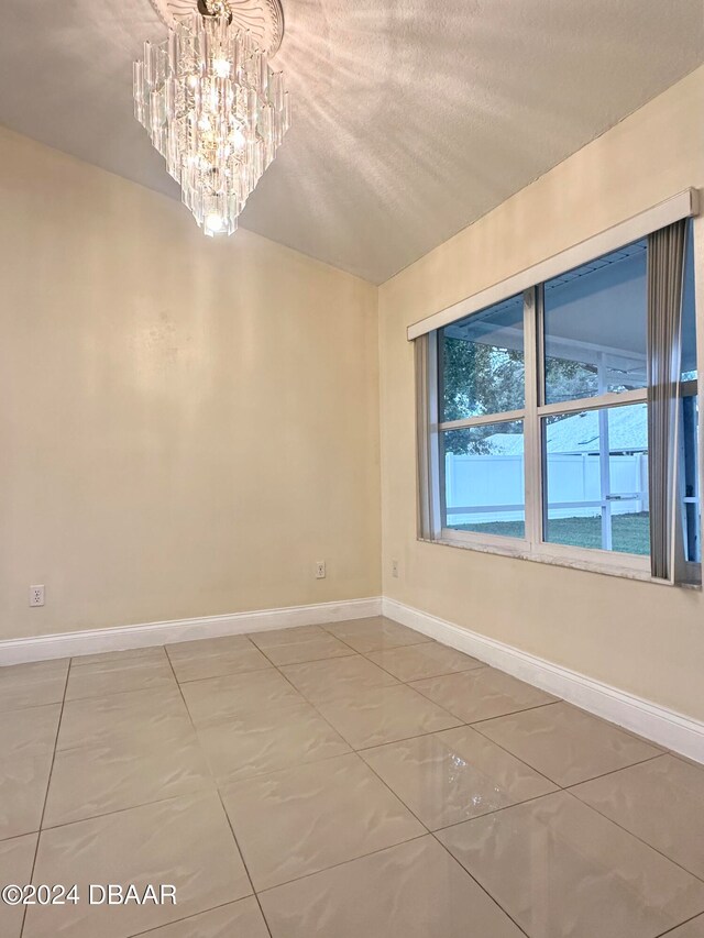 5 Wild Rose Pl, Palm Coast, FL 32164 - empty room with tile patterned flooring, a textured ceiling, vaulted ceiling, and an inviting chandelier
