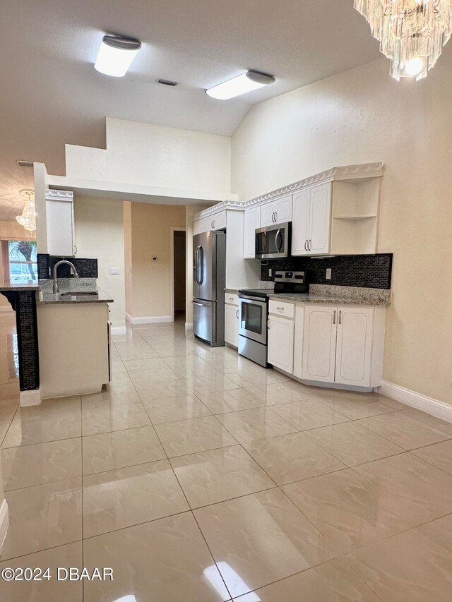 5 Wild Rose Pl, Palm Coast, FL 32164 - kitchen featuring stainless steel appliances, sink, kitchen peninsula, white cabinets, and vaulted ceiling