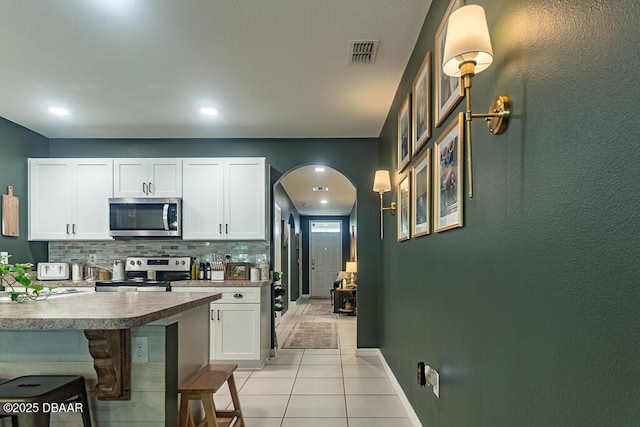 2756 Star Coral Ln, New Smyrna Beach, FL 32168 - kitchen featuring appliances with stainless steel finishes, white cabinets, backsplash, arched walkways, and baseboards