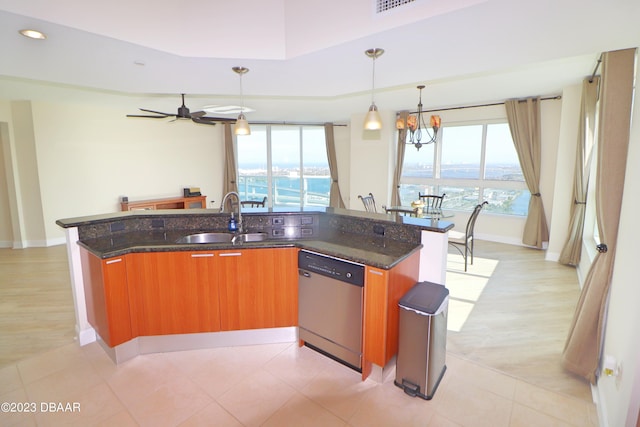 kitchen with a center island with sink, decorative light fixtures, sink, stainless steel dishwasher, and a water view