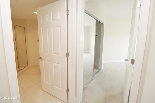 hallway featuring light tile patterned flooring, light carpet, and baseboards