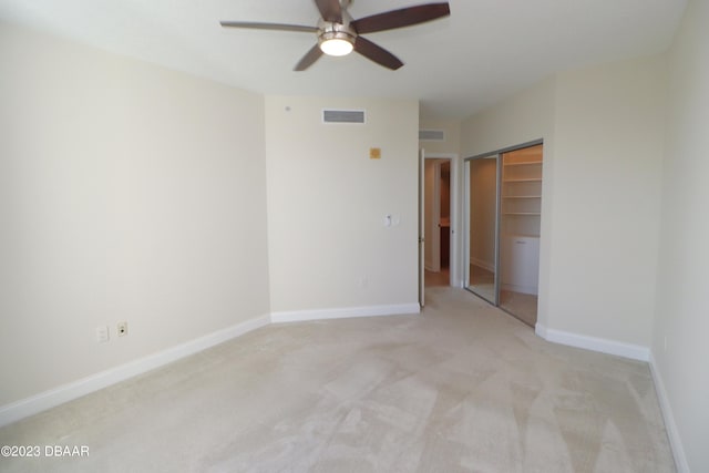 unfurnished bedroom with visible vents, a closet, baseboards, light colored carpet, and ceiling fan