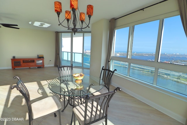 dining room featuring a water view, a notable chandelier, and light hardwood / wood-style floors