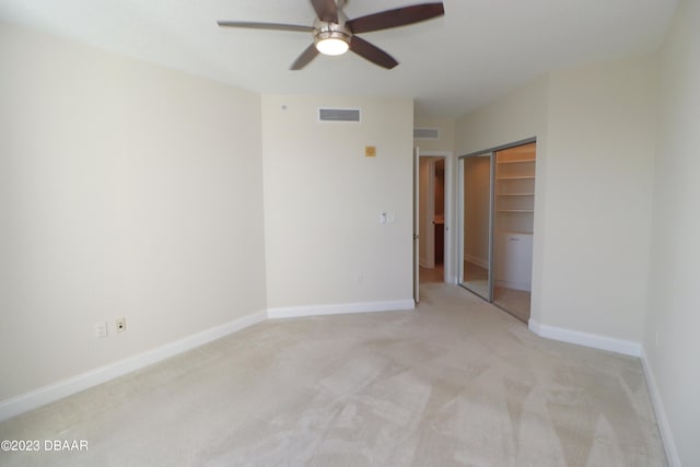 unfurnished bedroom featuring light carpet, ceiling fan, and a closet