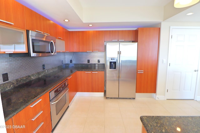 kitchen featuring dark stone counters, appliances with stainless steel finishes, decorative backsplash, and light tile patterned floors