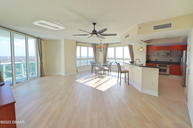 kitchen featuring stainless steel appliances, backsplash, light hardwood / wood-style floors, a water view, and ceiling fan with notable chandelier