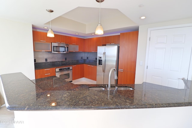 kitchen featuring pendant lighting, kitchen peninsula, stainless steel appliances, and tasteful backsplash