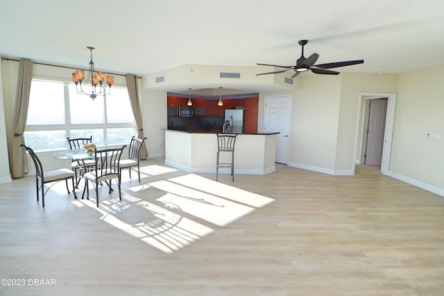 dining room with ceiling fan with notable chandelier and light wood-type flooring