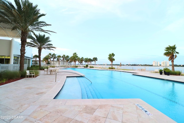 view of swimming pool with a patio and a water view