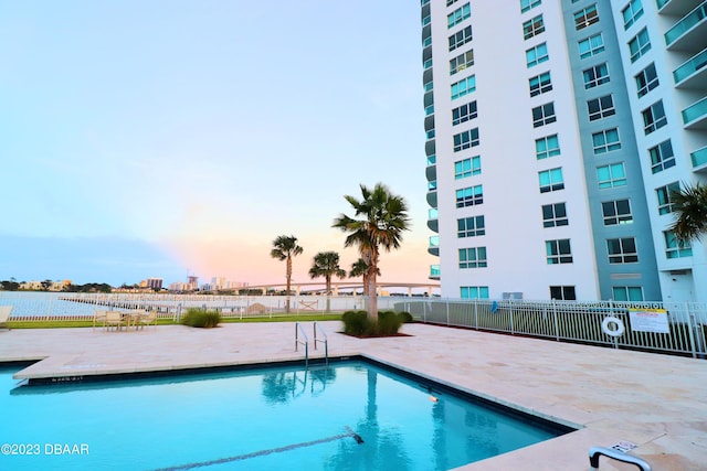 231 Riverside Dr Unit 2409, Holly Hill, FL 32117 - pool at dusk with a community pool, fence, a water view, and a patio