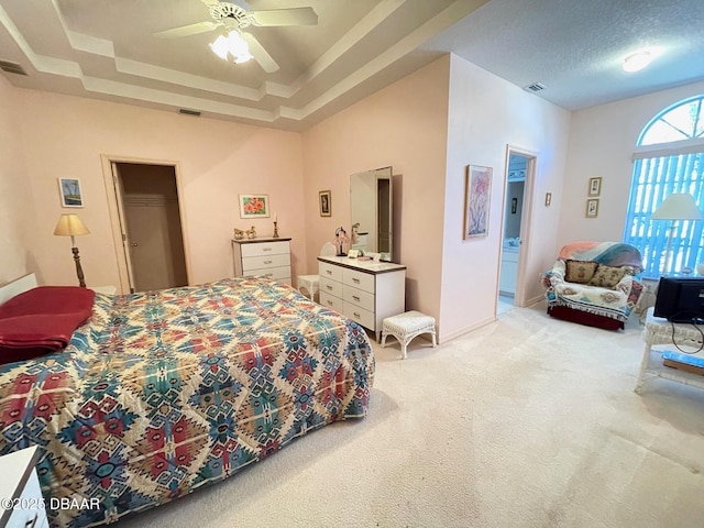 bedroom with light carpet, a textured ceiling, a raised ceiling, and ceiling fan