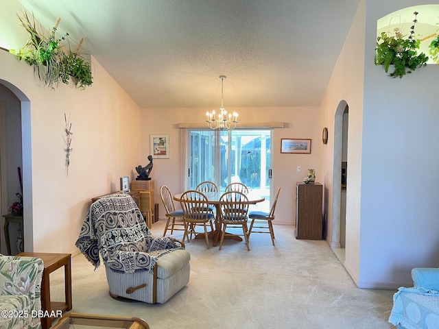 dining room featuring light colored carpet, a notable chandelier, and a textured ceiling