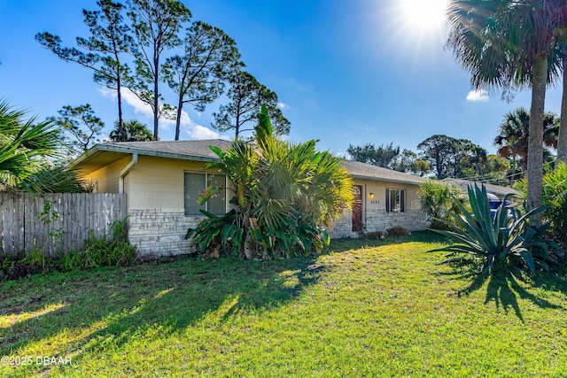 view of front facade featuring a front yard, stone siding, and fence